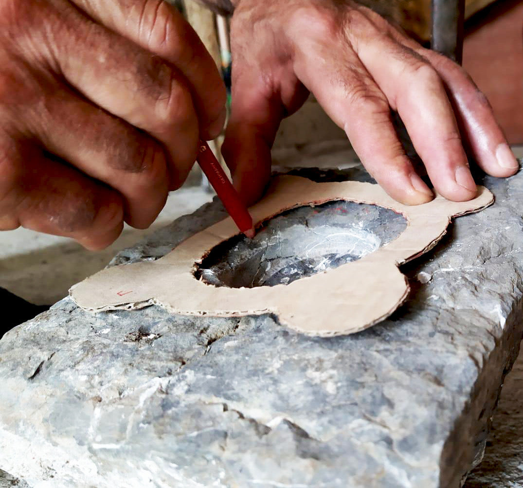 un artigiano in Calabria che disegna e progetta il suo manufatto sulla pietra prima di scolpirla